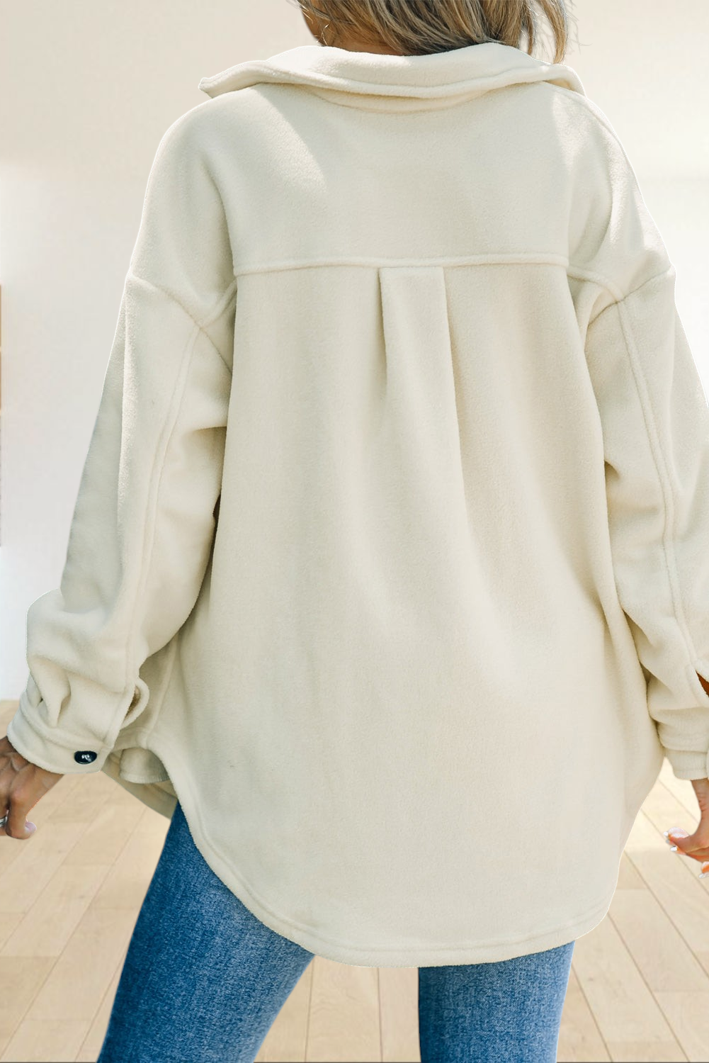 Baya Wear beige fleece shirt jacket featuring a back yoke, curved hem, and oversized fit worn with blue denim jeans.