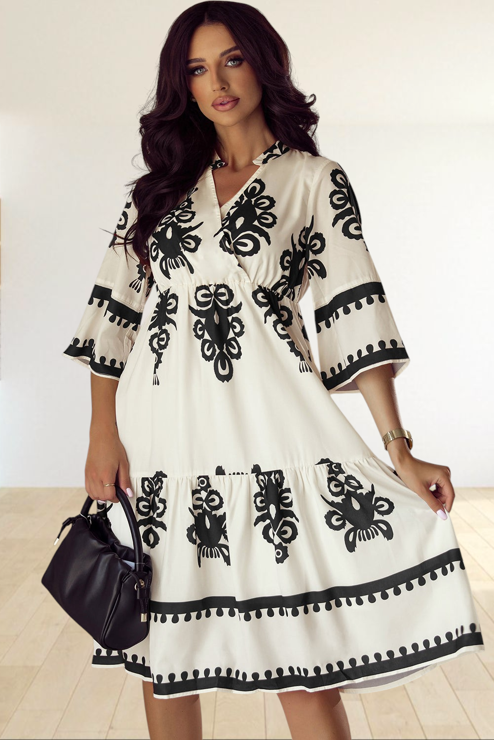 Baya Wear beige midi dress with black geometric print, V-neckline, and 3/4 sleeves worn by a woman holding a bag.