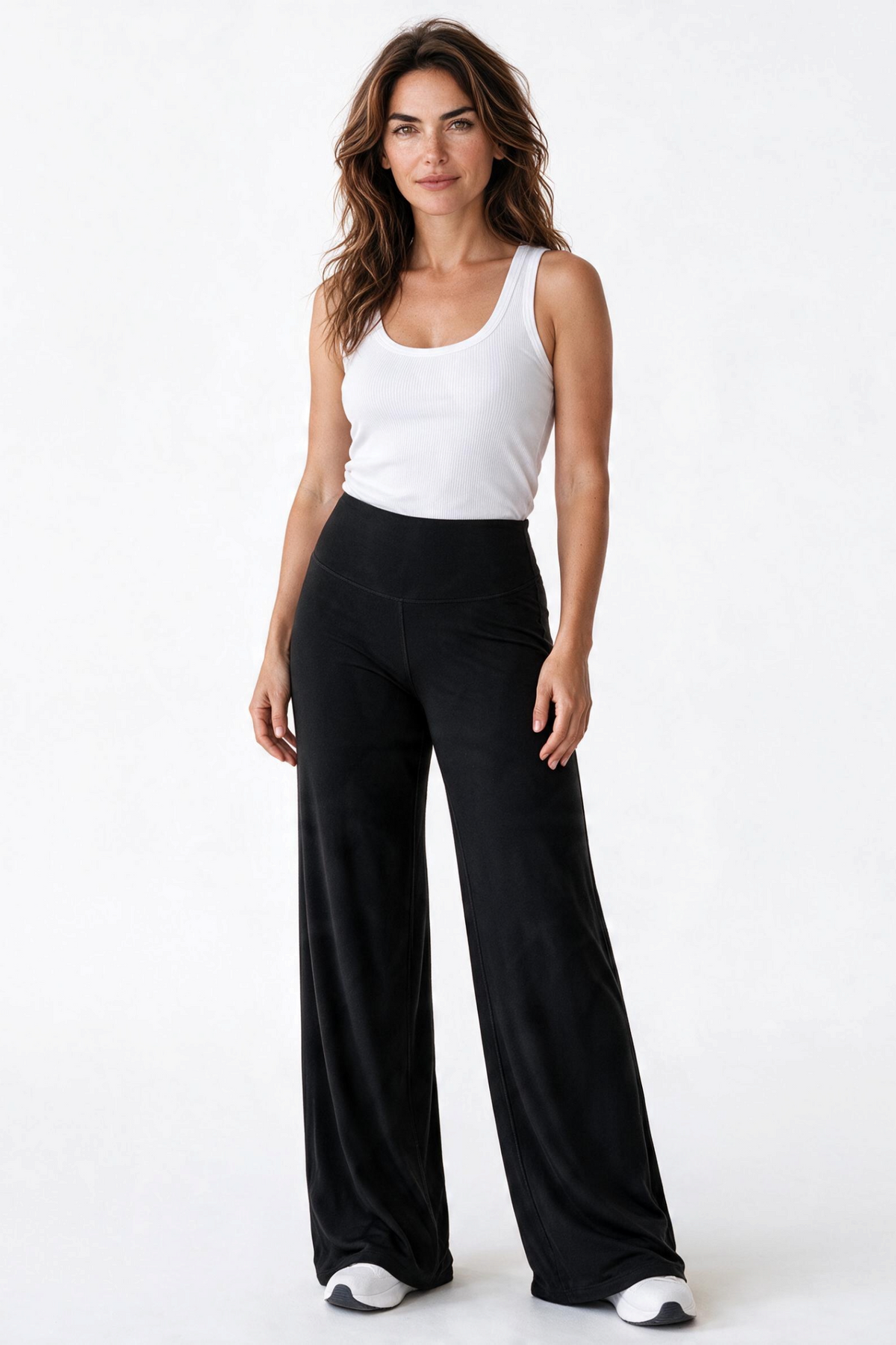 Baya Wear high-waisted black wide leg yoga pants worn by a woman with a white tank top against a white background
