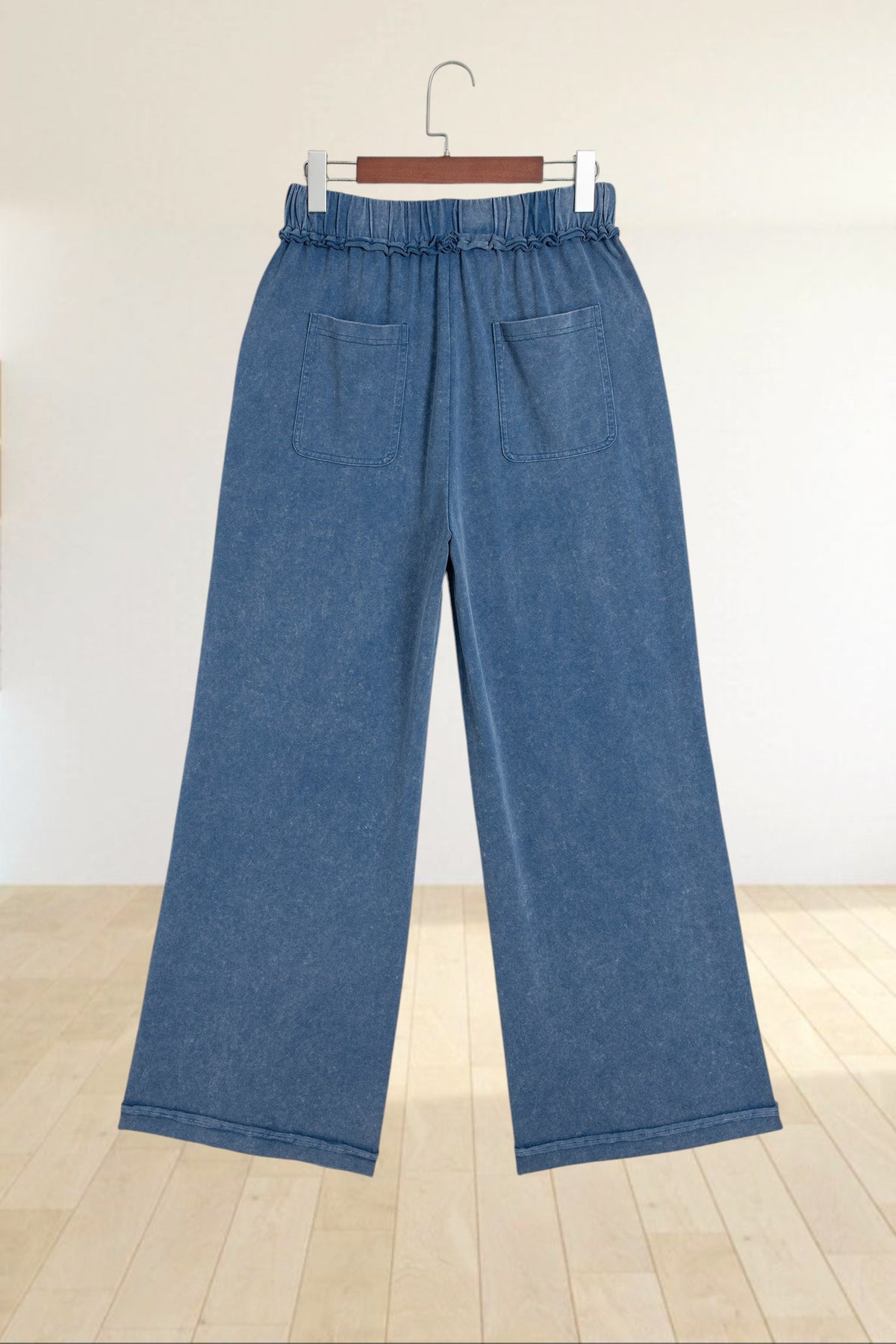 Baya Wear blue mineral wash wide leg lounge pants with a drawstring waist and back pockets hanging on a hanger.