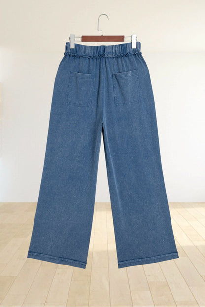 Baya Wear blue mineral wash wide leg lounge pants with a drawstring waist and back pockets hanging on a hanger.