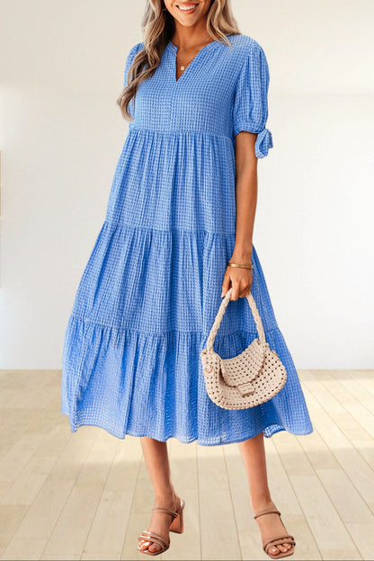 Baya Wear blue textured gingham tiered midi dress with V-neck, short sleeves with bow ties, and side pockets.