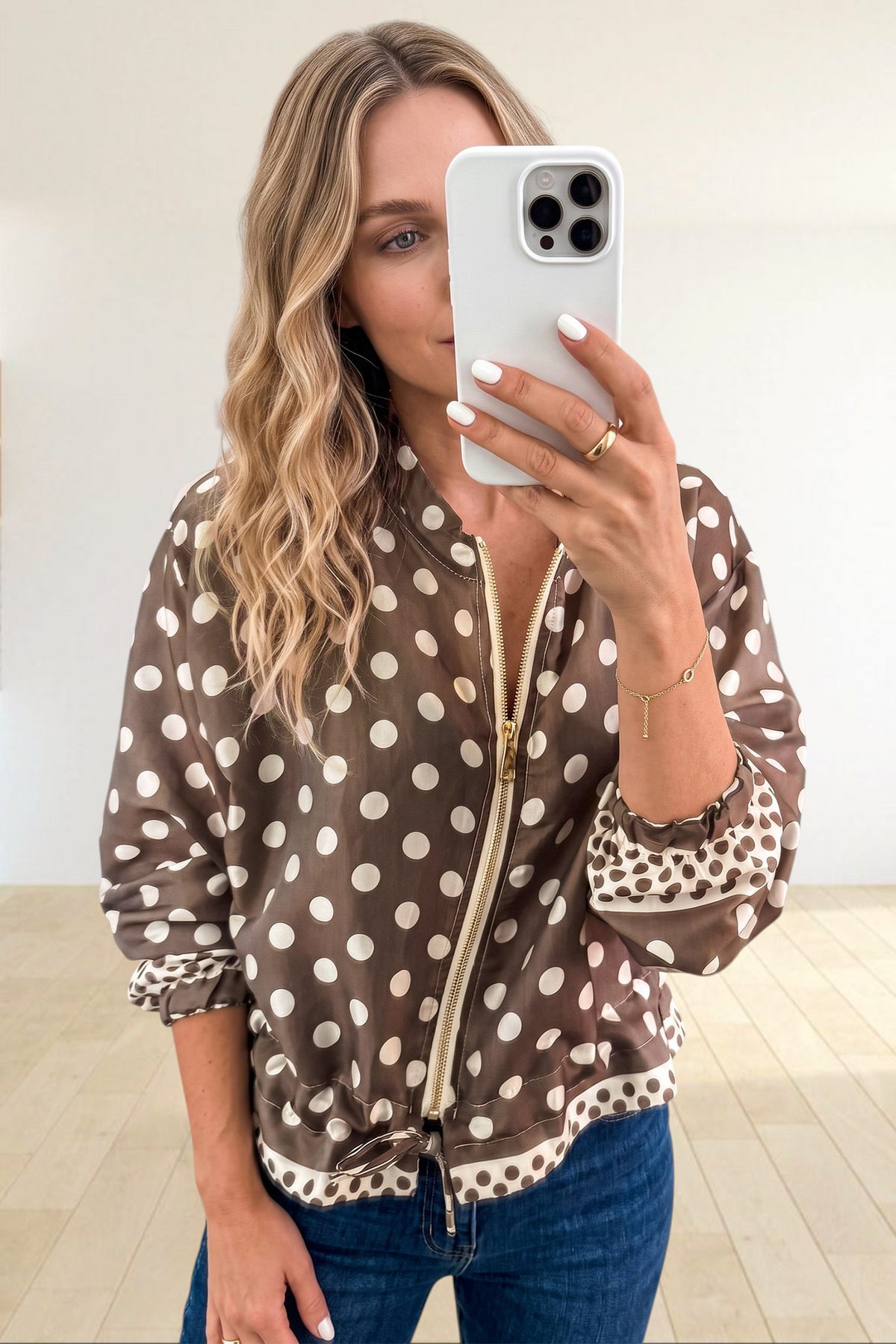 Baya Wear brown polka dot zip-up bomber jacket with gold hardware and contrast cuffs worn by a woman in a mirror.