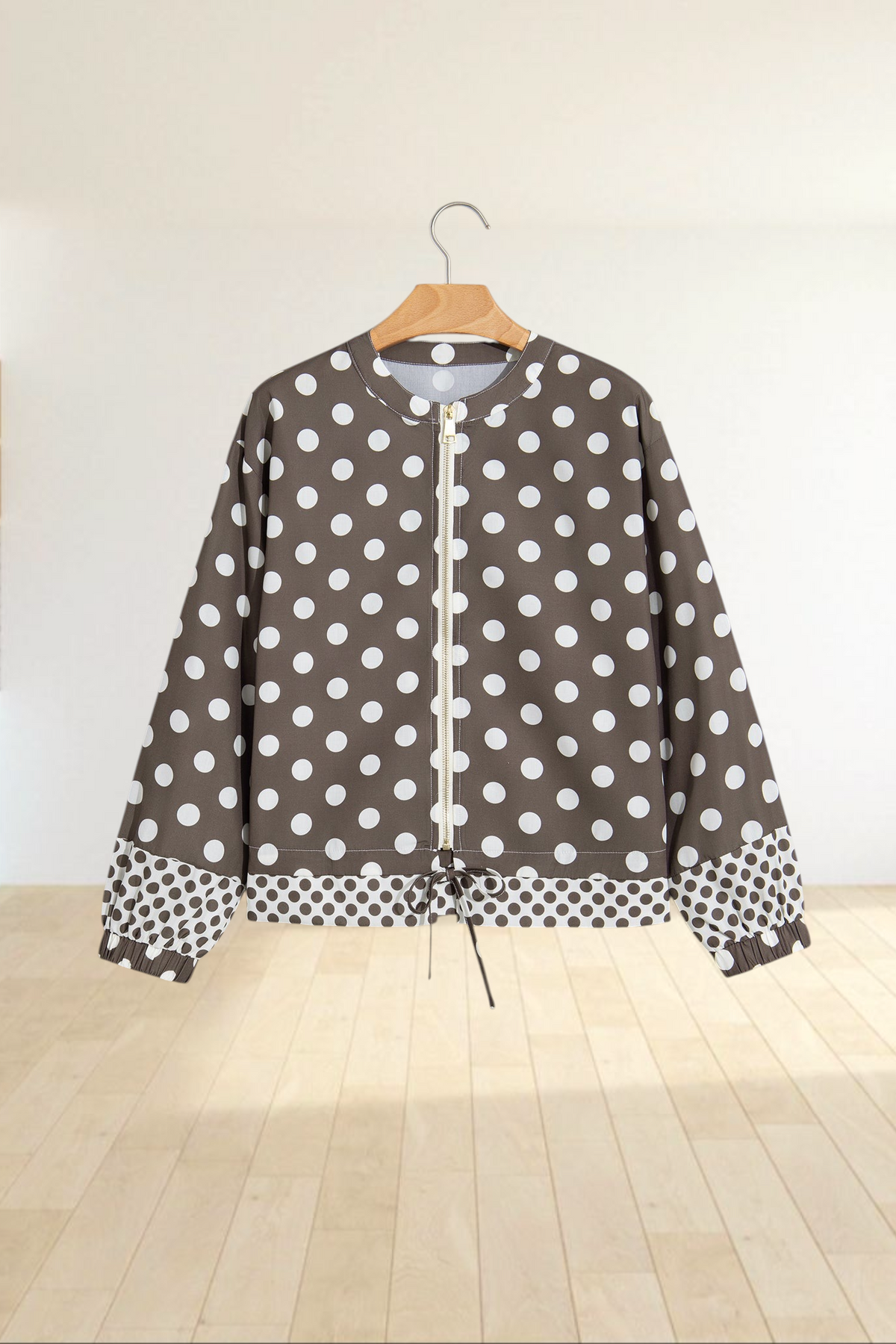Baya Wear brown zip-up bomber jacket with white polka dots, gold hardware, and contrast pattern hem on a hanger.
