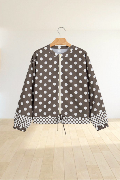 Baya Wear brown zip-up bomber jacket with white polka dots, gold hardware, and contrast pattern hem on a hanger.