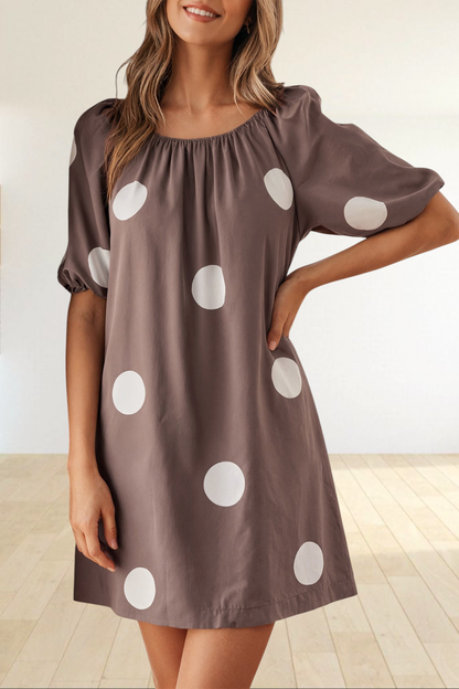 Baya Wear brown mini dress with white polka dots, gathered neckline, and puff sleeves worn by a woman outdoors