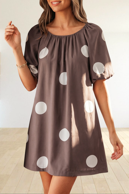 Baya Wear brown mini dress with white polka dots, gathered neckline, and short puff sleeves worn by a woman