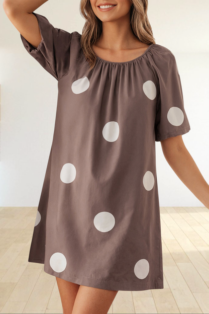 Baya Wear brown mini dress with white polka dots, gathered neckline, and short puff sleeves worn by a smiling model.