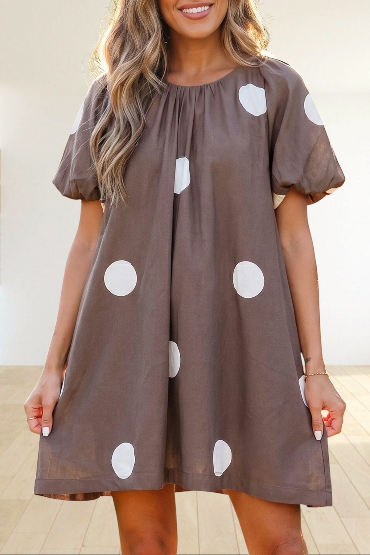 Baya Wear brown mini dress with white polka dots, gathered neckline, and short puff sleeves worn by a woman outdoors.