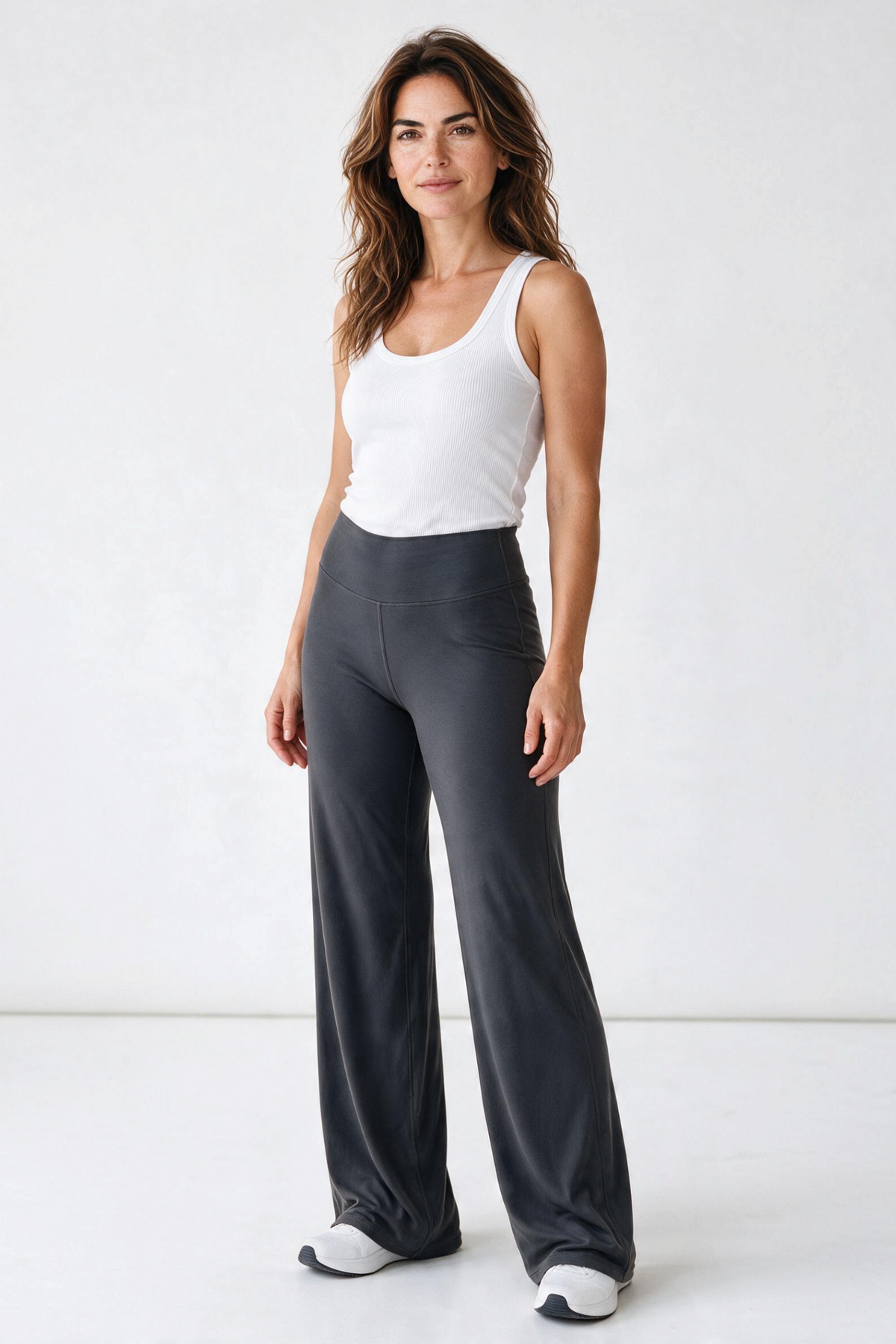 Baya Wear high-waisted wide leg yoga pants in charcoal grey worn by a woman with a white tank top