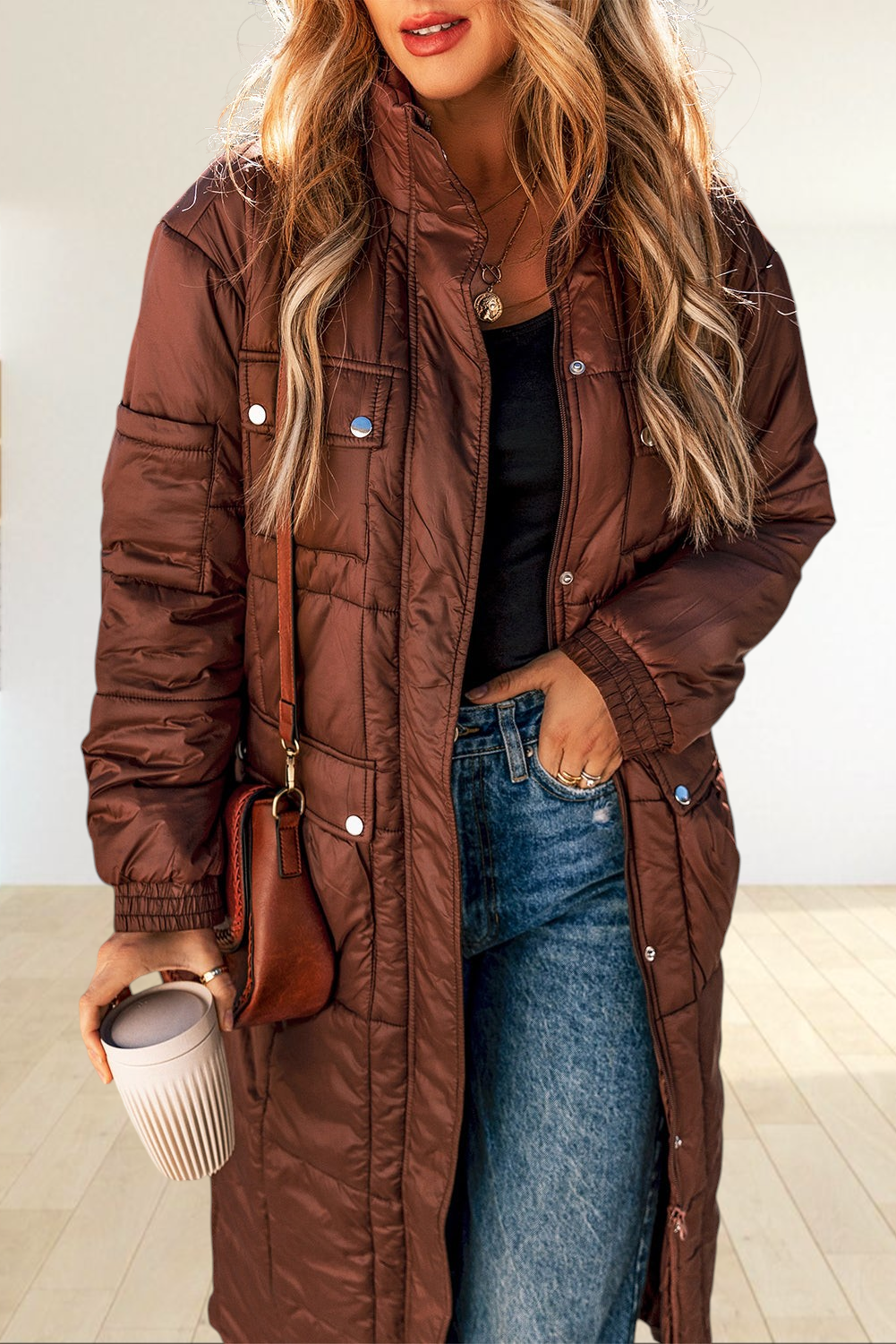 Baya Wear coffee brown mid-length quilted puffer jacket with stand neck, zip closure, and flap pockets on a woman.