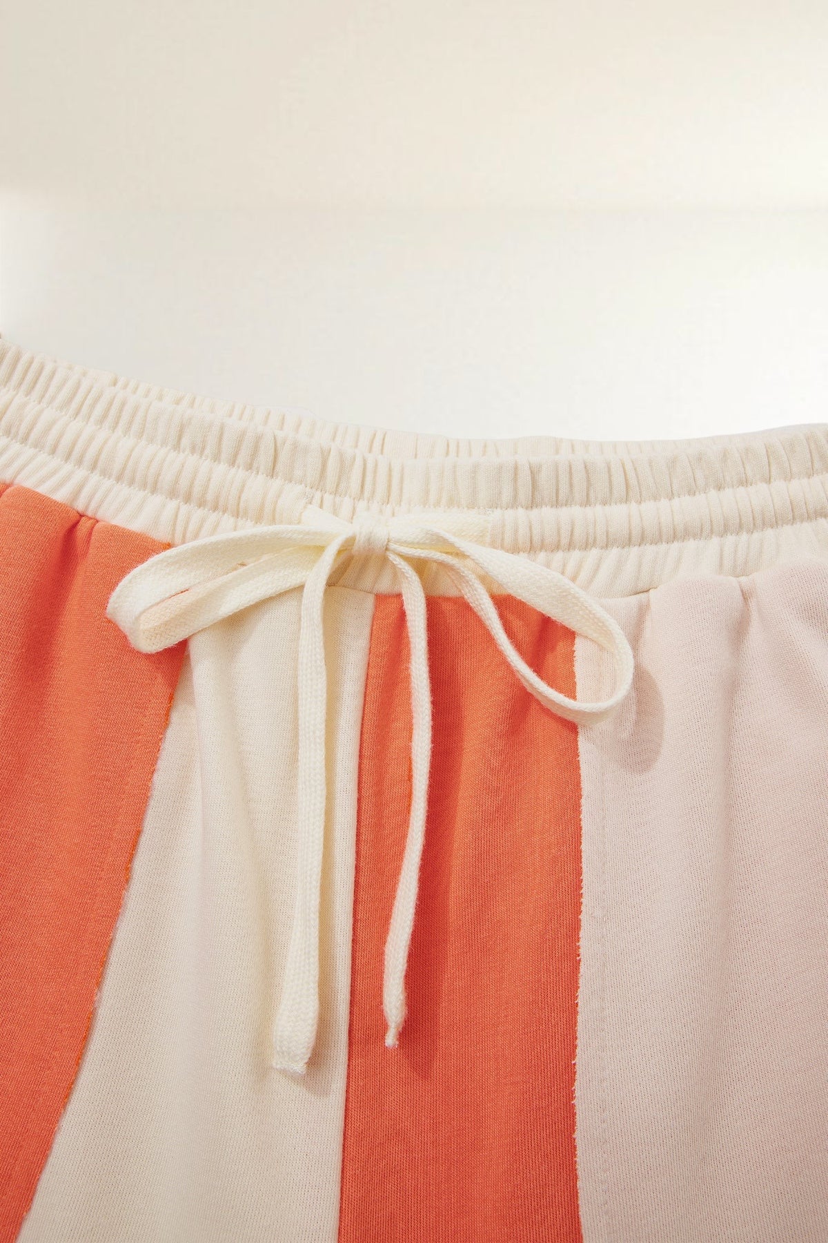 Baya Wear color block lounge pants with an elastic drawstring waistband and raw-edge seams in orange and cream
