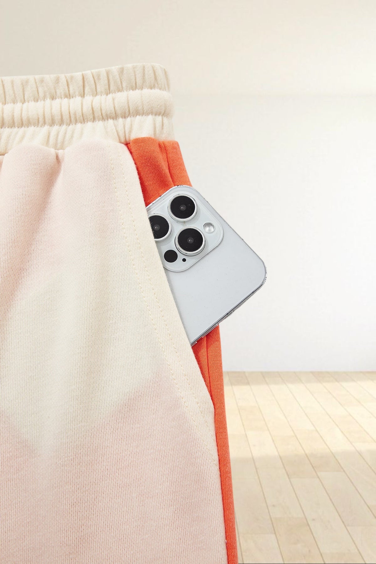 Baya Wear color block lounge pants featuring a cream elastic waistband and a side pocket holding a smartphone
