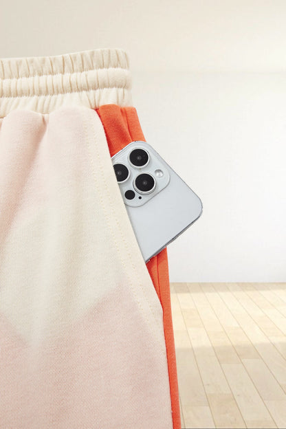 Baya Wear color block lounge pants featuring a cream elastic waistband and a side pocket holding a smartphone