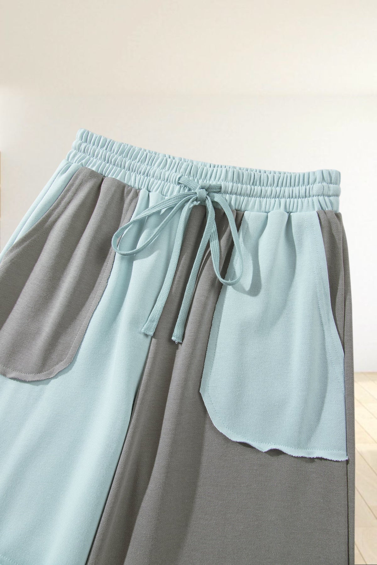 Baya Wear color block wide-leg lounge pants in light blue and grey with an elastic drawstring waist and patch pockets.