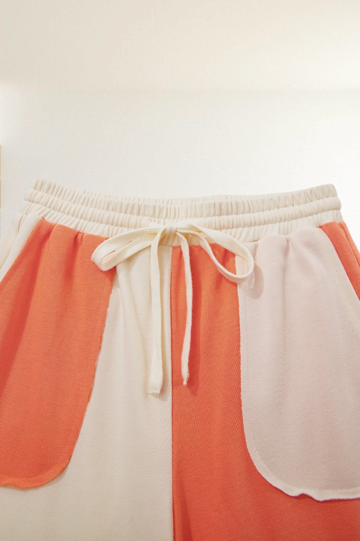 Baya Wear color block wide-leg lounge pants in cream and orange with an elastic drawstring waist and raw-edge pockets.