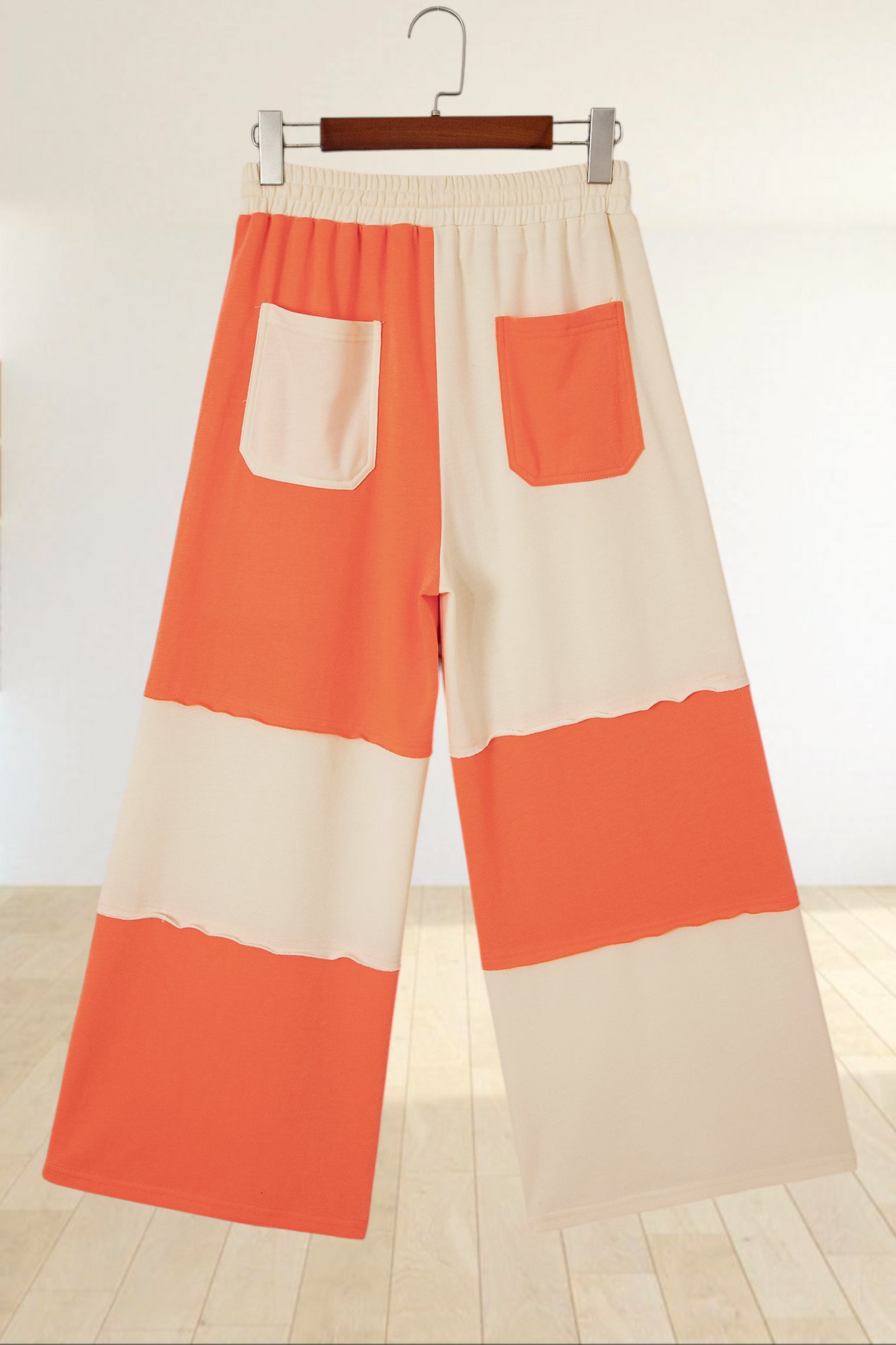 Baya Wear color block wide-leg lounge pants in orange and cream with raw-edge seams and back patch pockets.