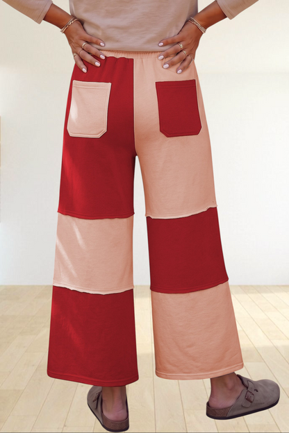 Baya Wear wide-leg lounge pants featuring a red and beige colorblock patchwork design with raw-edge seams and pockets.