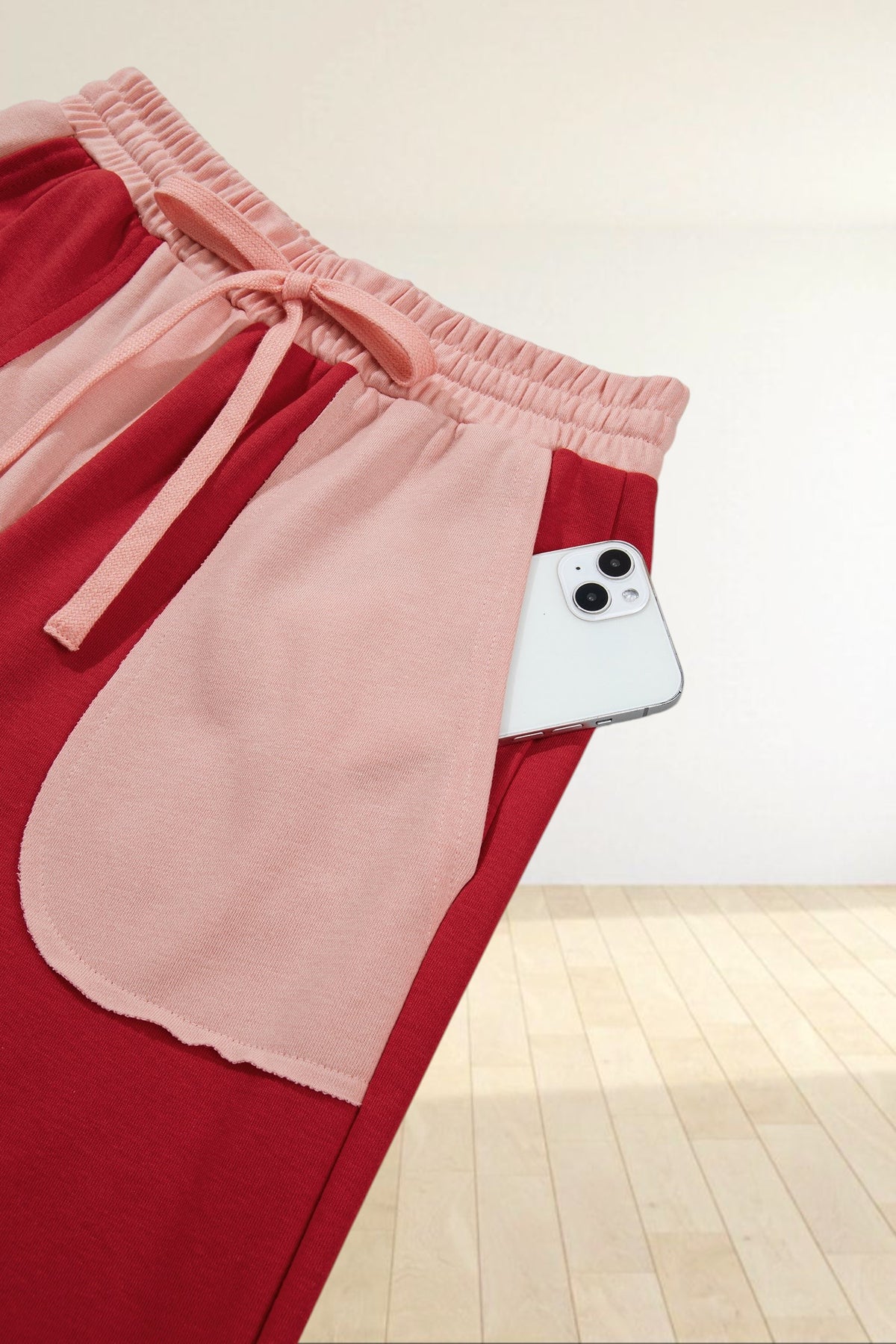 Baya Wear color block lounge pants in red and light pink with a drawstring waist and large side pocket holding a phone