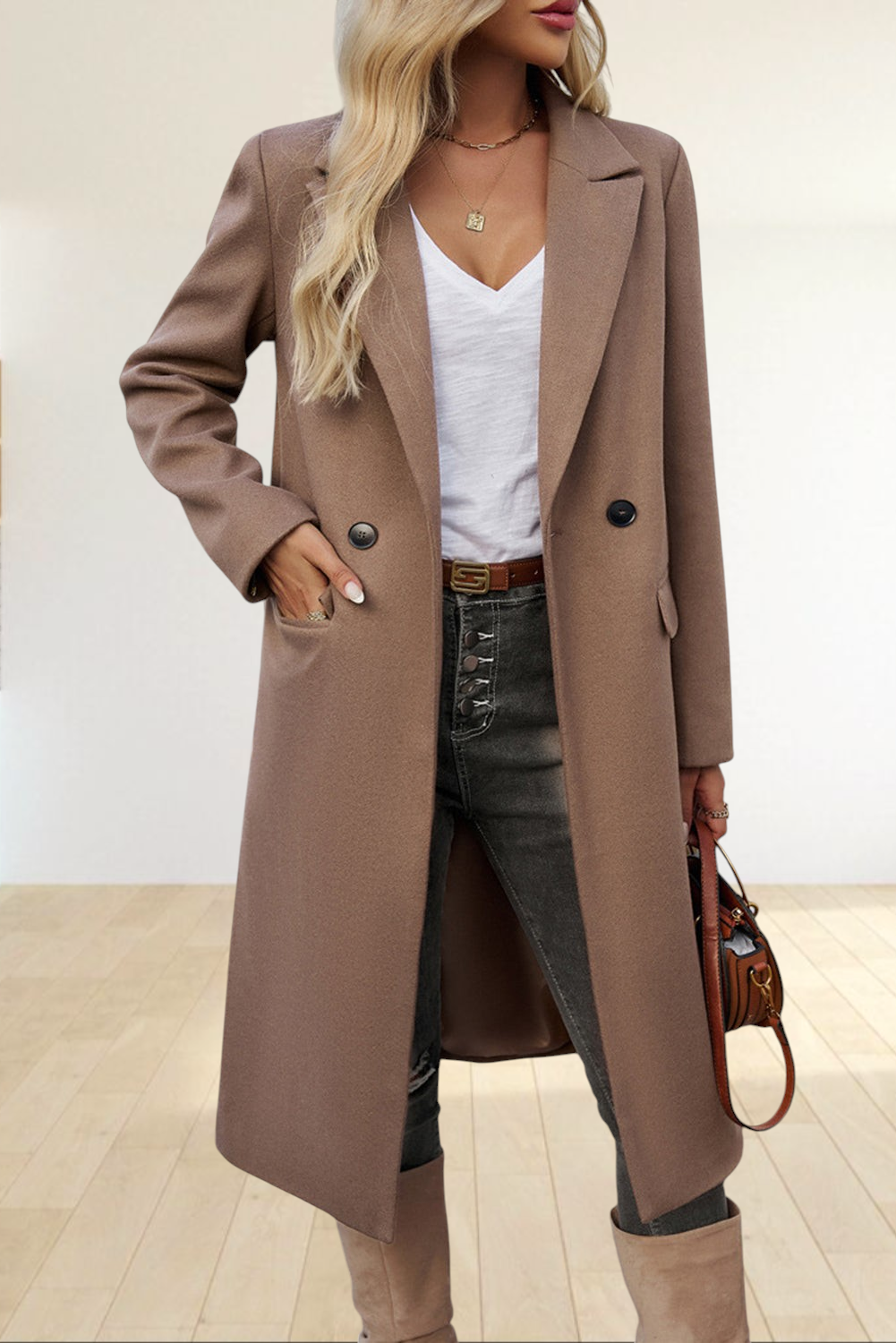 Baya Wear dark khaki single-breasted longline overcoat with lapel collar and flap pockets worn over jeans and boots.