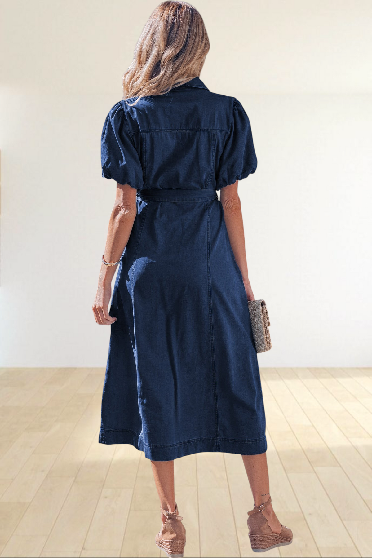 Baya Wear dark blue denim midi dress with puff sleeves and tie-waist belt, worn by a woman on a sunny sidewalk.