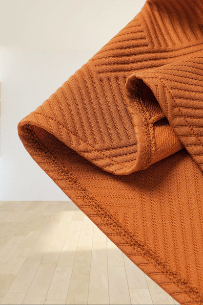 Close-up of Baya Wear gold flame textured duster coat fabric showing geometric pattern and soft material detail