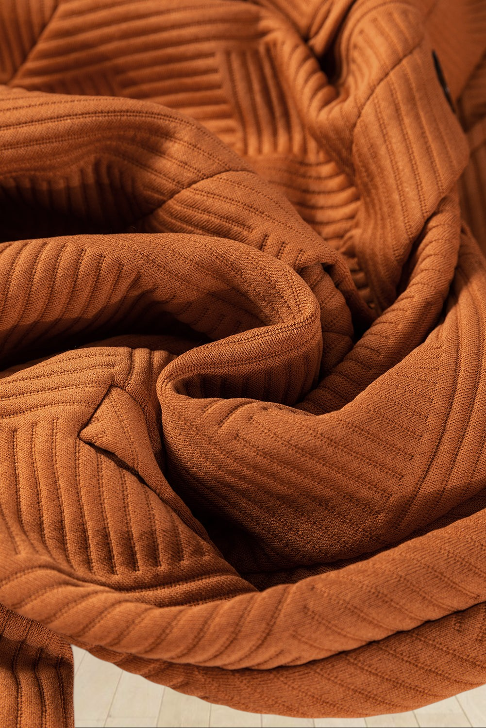 Close-up of Baya Wear gold flame textured fabric showing geometric ribbed patterns and soft, draped material.