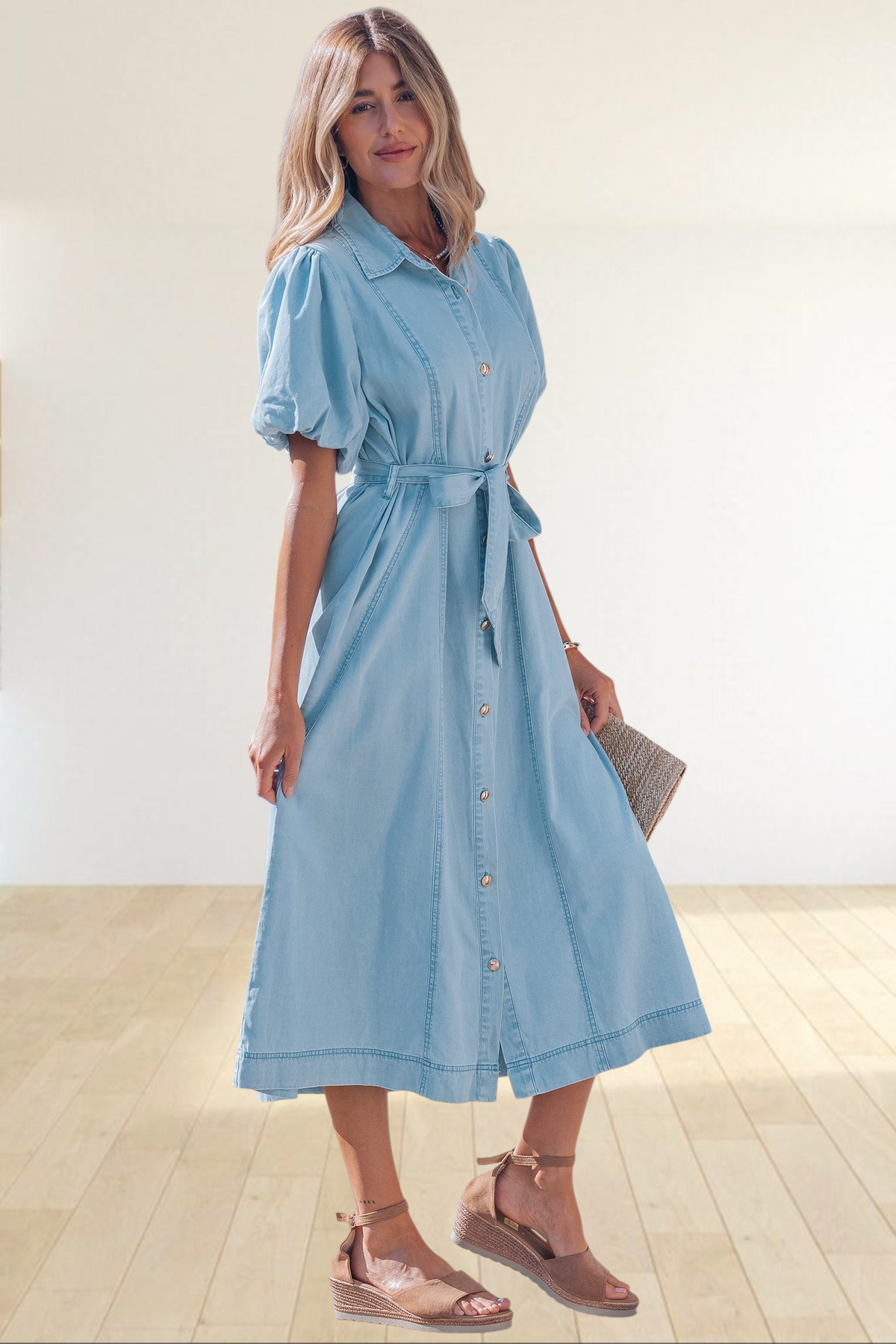 A woman wearing a Baya Wear light blue denim midi dress with puff sleeves, a button-down front, and a tie-waist belt.