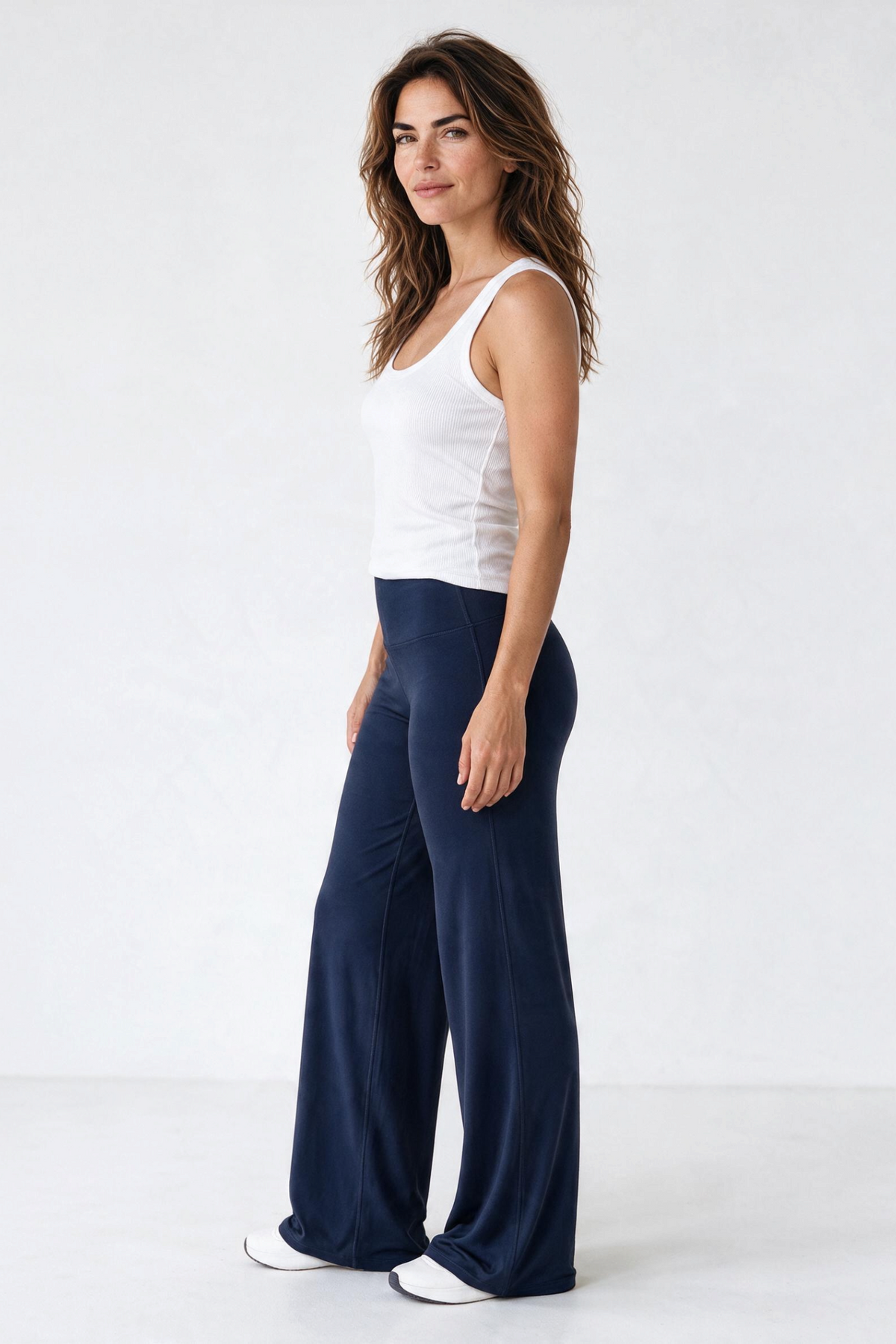 Baya Wear high-waisted navy blue wide leg yoga pants worn by a woman with a white tank top in a studio setting
