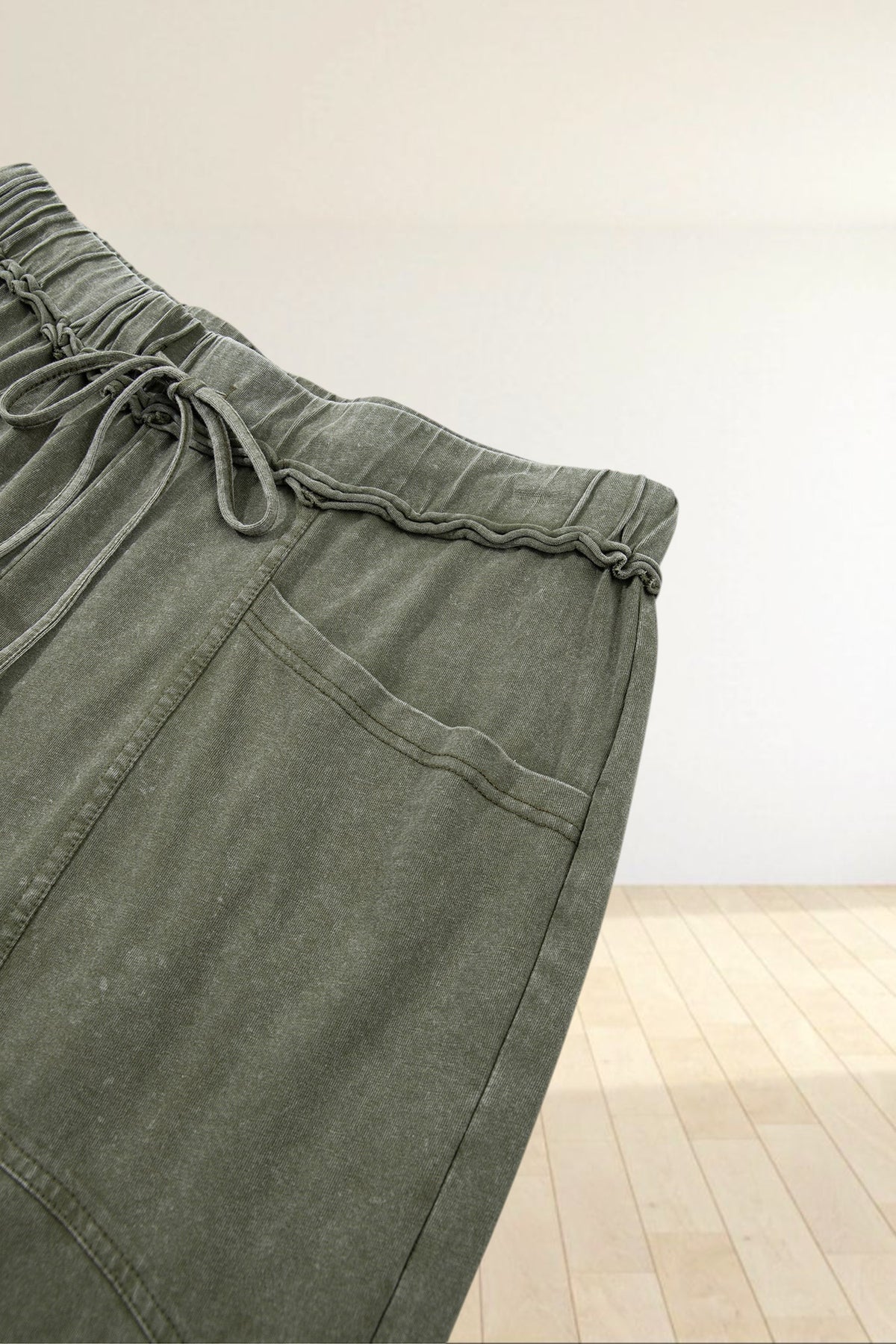 Baya Wear olive green mineral wash lounge pants featuring a drawstring waist, seam detailing, and side pockets.