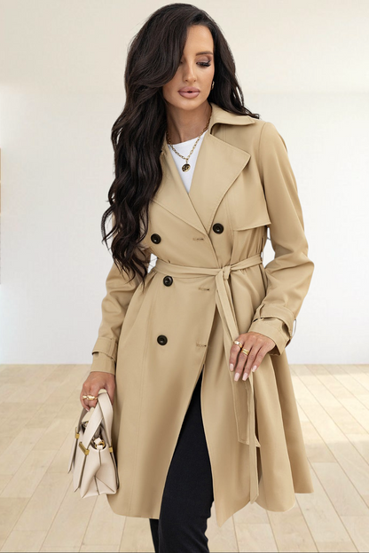 Baya Wear pale khaki double-breasted trench coat with lapel collar and waist-tie belt worn by a woman