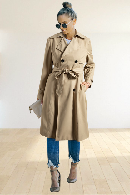 Baya Wear pale khaki double breasted trench coat with a waist-tie belt worn by a woman with jeans and heels