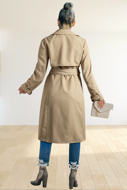Baya Wear pale khaki double-breasted trench coat with a waist-tie belt, worn by a woman from the back view.