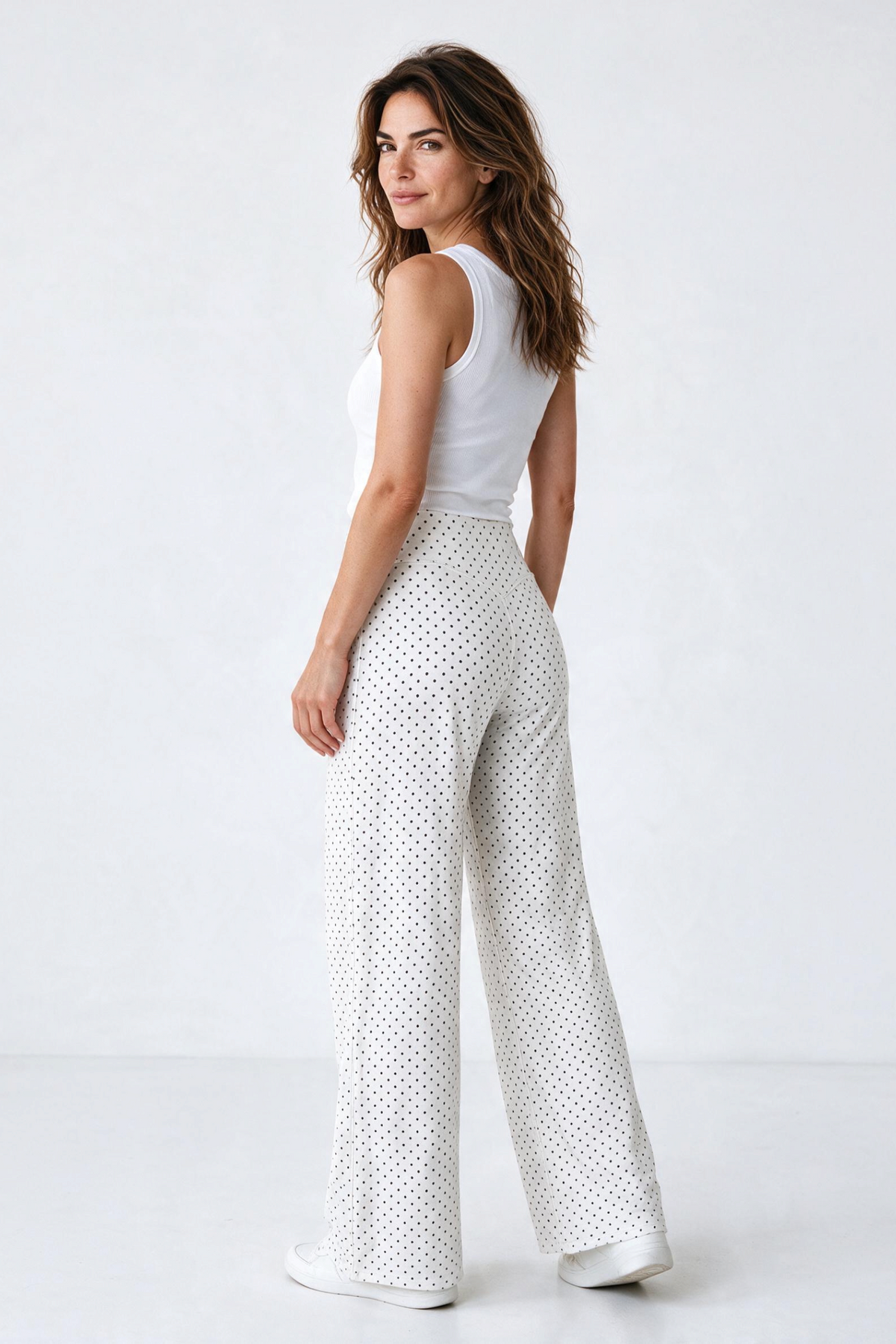 Baya Wear high-waisted wide leg pants in white with black polka dots, worn by a woman with a white tank top