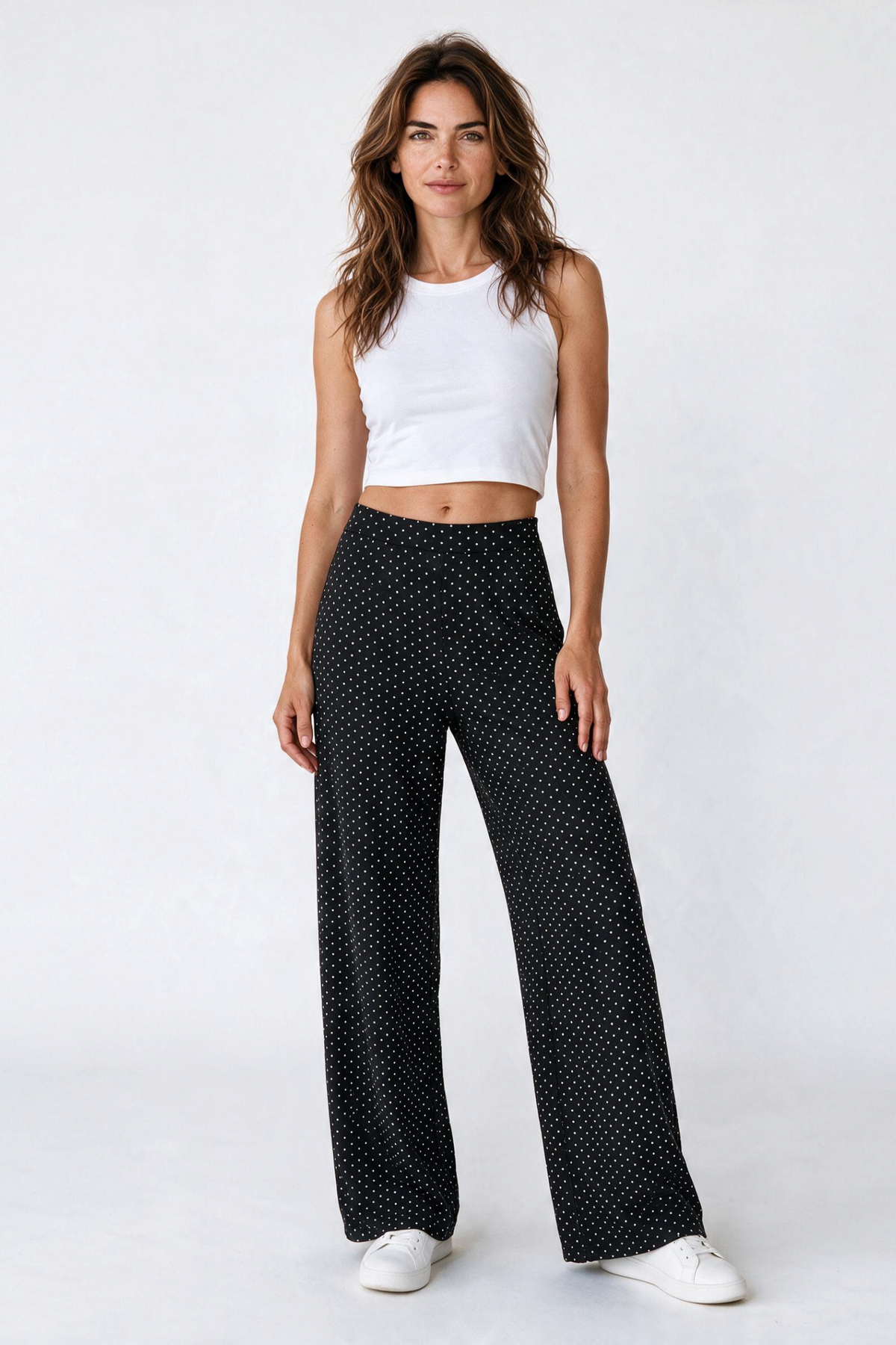 Baya Wear high-waisted wide leg pants in black with white polka dots, paired with a white crop top and sneakers.