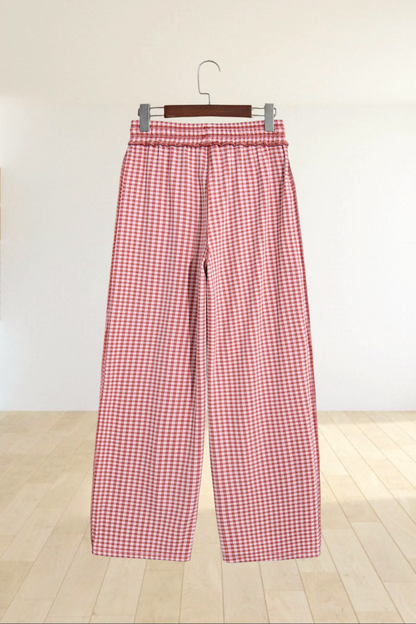 Baya Wear red and white gingham wide leg lounge pants with an elastic drawstring waist hanging on a wooden hanger.