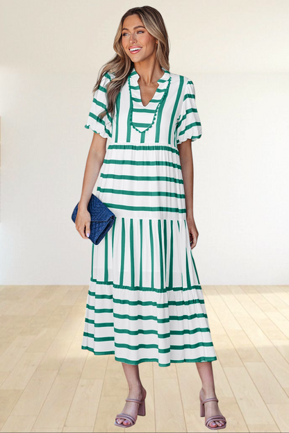 Baya Wear tiered midi dress in white and green stripes with a notched neckline and ricrac trim, worn by a woman.