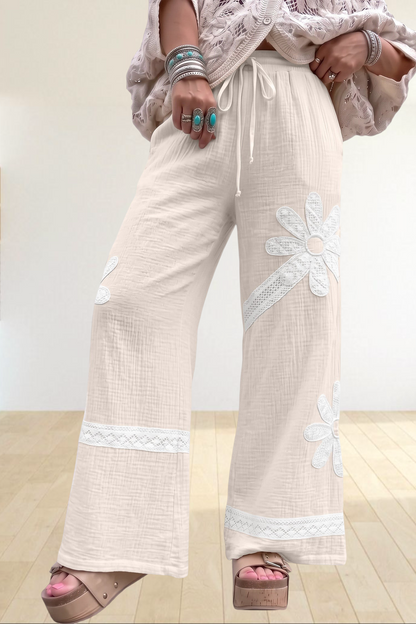 Baya Wear white wide-leg trousers featuring floral lace patchwork, drawstring waist, and soft textured fabric.