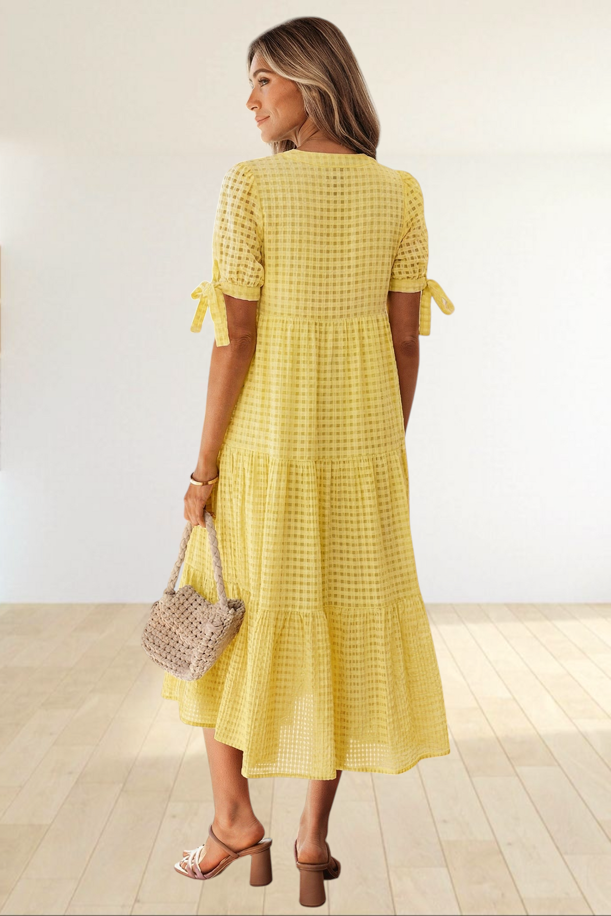 Baya Wear yellow textured gingham tiered midi dress with short sleeves and bow-tie details on a woman from behind