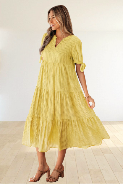 Baya Wear yellow textured gingham midi dress with tiered skirt, V-neckline, and short sleeves with bow-tie details.